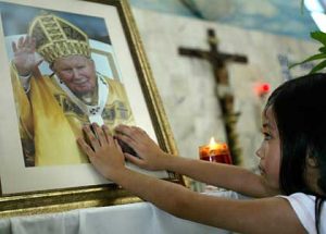 A young Malaysian touches a photograph of Pope John Paul II after a mass at a church in Kuala Lumpur, Malaysia, Sunday, April 3, 2005. Mass services at Catholic churches in Malaysia saw more parishes than usual Sunday following news of the Pope's death. (AP Photo/Teh Eng Koon)